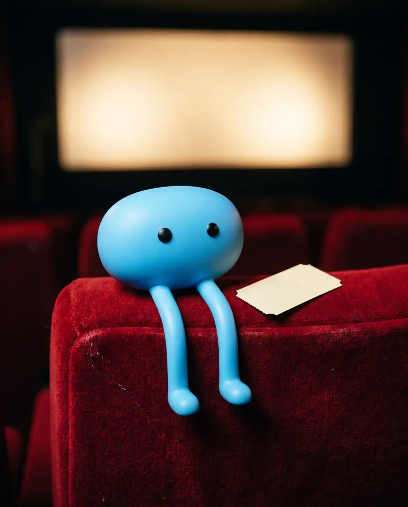 Chipo sitting on a red cinema seat with a ticket